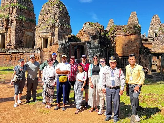 Tour group and guide posing at the red sandstone ruins of Banteay Srei