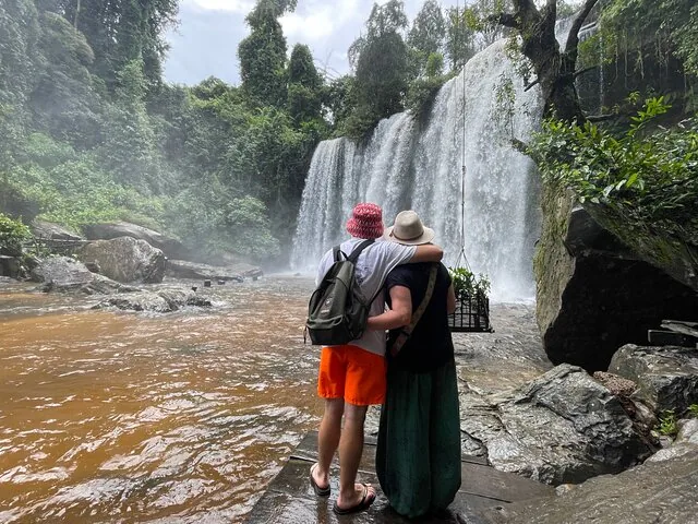Couple embracing while looking at a powerful waterfall in the jungle