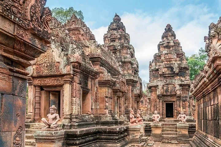 Intricately carved red sandstone towers and guardian statues at Banteay Srei