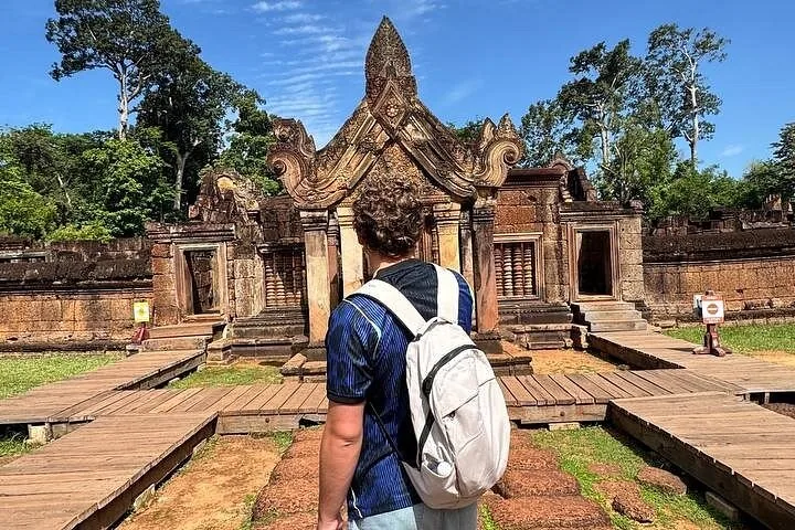 Tourist with backpack looking at the ornate entrance of Banteay Srei